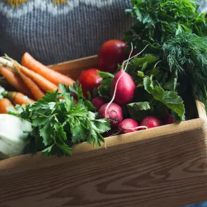 Woman holding carton of vegetables.