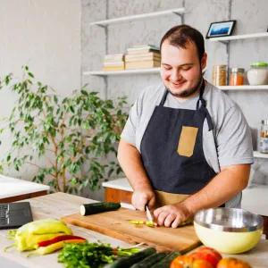 A man cutting up vegetables in his kitchen.