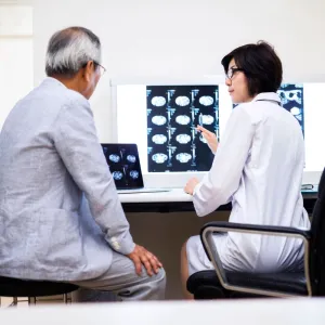 A doctor reviews brain scans with the older male patient