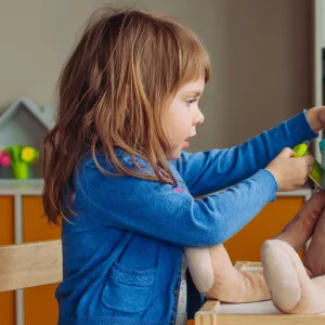 A child playing doctor with a stuffed animal.