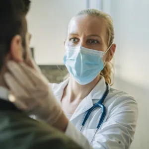 A doctor examines a patient while wearing a mask.