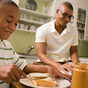 Father and son make peanut butter sandwiches together.