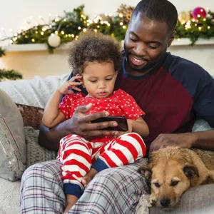 A father an son sit together on the couch during the holiday season.