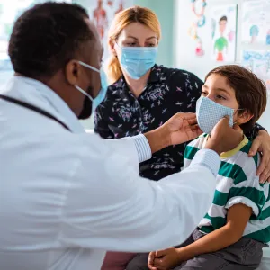 Mother and son at a doctor's office while wearing masks.
