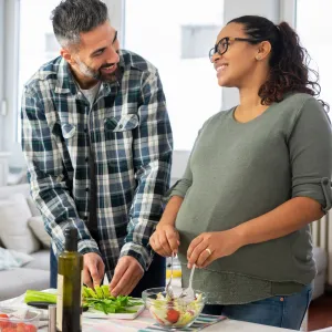 A pregnant woman and her husband make a healthy meal.