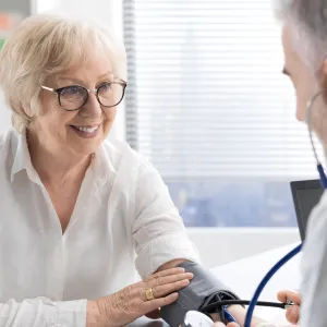 An older woman having her blood pressure checked by a doctor.