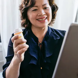 A woman holding a tablet and talking to her doctor about her prescription on a video call.