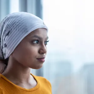 A young woman with cancer staring out the window.