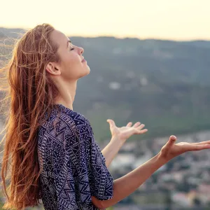 A young woman gives praise to God outside