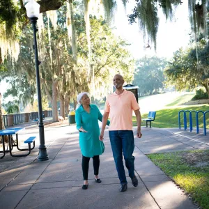 A Couple Walks Through a Park By a Lake in Clermont Florida, Laughing and Enjoying the Outdoors.