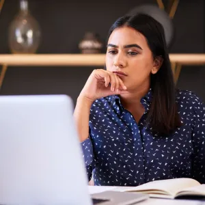 A woman looking thoughtfully at her laptop