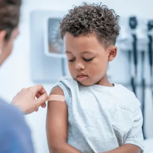A young boy getting a band-aid after a flu shot.