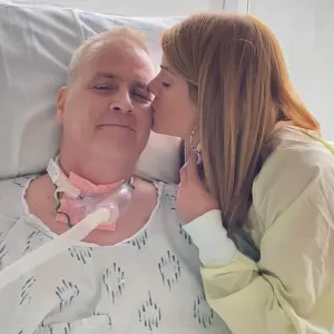 Karen Wilkinson gives her husband David a kiss on the cheek while he's in the hospital.
