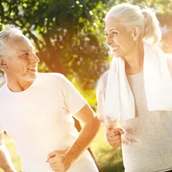 An older couple goes jogging outdoors.