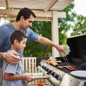 A father and son grilling on the porch.
