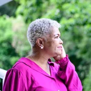 An older woman talking on the phone outdoors.