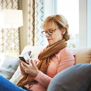 Senior woman using phone on couch at home