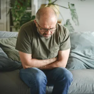 Man at home bent over holding stomach in pain.
