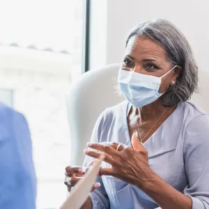 Masked Senior woman with physician