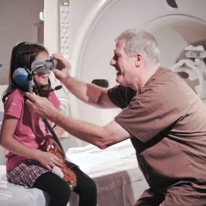 A male nurse puts MRI goggles on a girl.