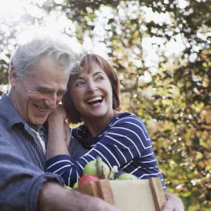 Senior couple smiling and embracing after picking up some apples