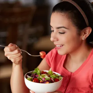 A woman eating a bowl of health food.