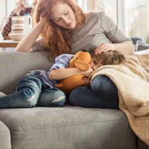 Sick child with mom on couch.