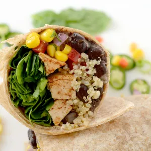 Half of Southwest chicken wrap lying on tortilla with jalapeno garnishes