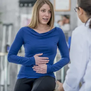 Woman with a stomach ache describes her symptoms to her doctor.
