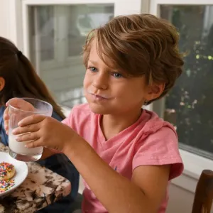 Three kids enjoy homemade cookies and milk