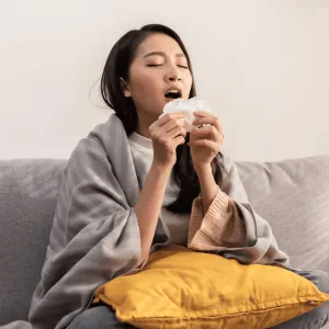 A woman sneezing into a tissue.
