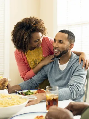 An African American family gathers around the dinner table for a meal of spaghetti.