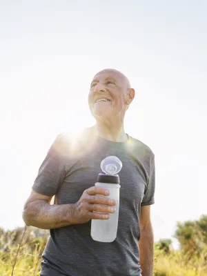 An older man takes a water break during a sunny outdoor hike