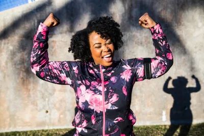 A Woman Triumphantly Flexes Her Arms After a Run in the Park