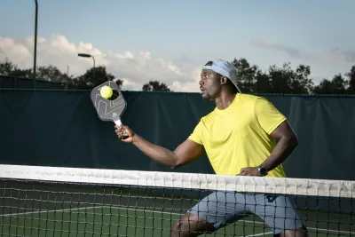 A Man Playing Pickleball on a Tennis Court