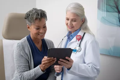 Doctor and patient holding tablet in medical office.