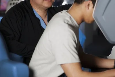 Two men looking at a robotic surgery control station.