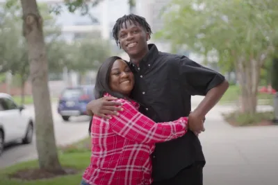 Antonio hugging his mother outside on a sidewalk.