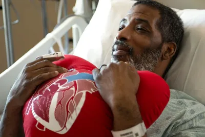 Patient holding heart shaped pillow in patient bed