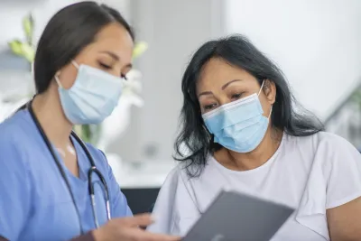 Doctor showing a patient how to schedule an appointment while wearing masks