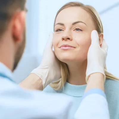 A doctor holds his hands to each side of a woman's face.
