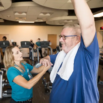 Will Cavins at the Research Institute Raises His Arm as a Trainer Checks His Other Arm