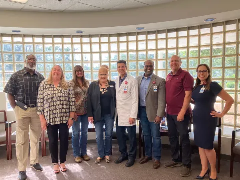 Clinic patients and cancer survivors, Teresa Ledford and Rena Weldon visits with AdventHealth physicians, leaders and State Representative Truenow.