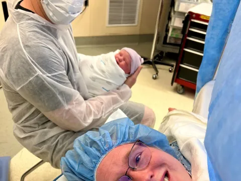 Meredith in her C-Section with her husband holding their newborn baby