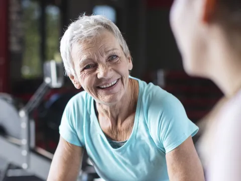 An older woman takes a break from working out on a rowing machine