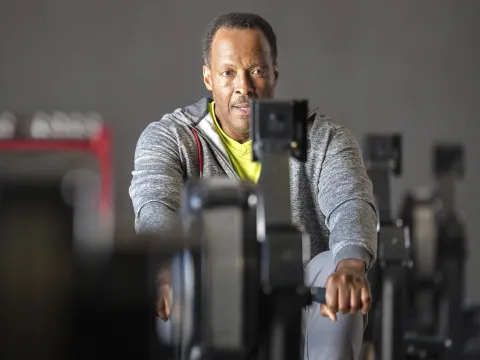 An older African American man works out on a rowing machine at the gym.
