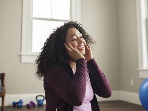 A young African American woman enjoys her music through her earbuds.