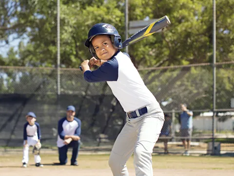 A young boy prepares to bat during an afternoon baseball game.