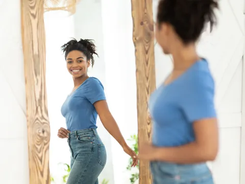 A young female adult looking at herself in the mirror