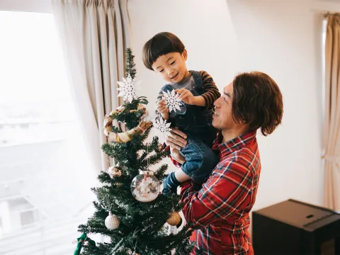 Father and son decorating a Christmas tree.